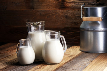 A jug of milk and glass of milk on a wooden table
