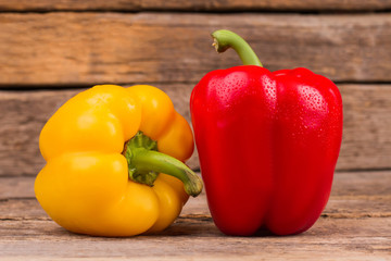 Two bell peppers, yellow and red. Close up. Old rustic wooden desk background.