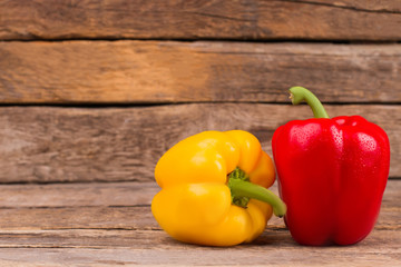 Fresh ripe bell peppers on wood. Yellow and red washed peppers with dew, old wooden background.