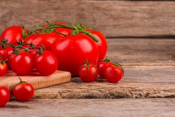 Many delicious cherry and vine tomatoes. Wooden cutting board and table.