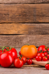 Orange tomato amoung red tomatoes. Colorful red and orange cherry tomatoes on wooden background.