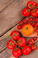 Red ripem tomatoes with vines. Yellow and red. Old rustic wooden desk, top view.