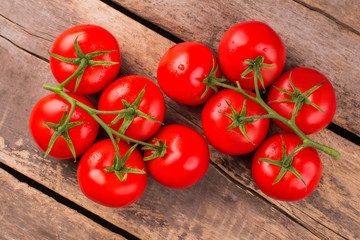 Two branches with ripe delicious tomatoes. Rustic wooden background. Top view.