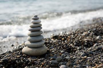 a pyramid of stones on a pebble beach on the background of the sea waves in the evening