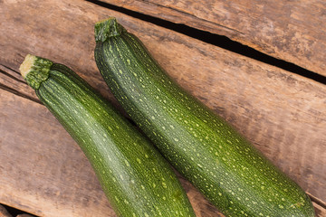 Two zucchini or courgettes on old wooden background. Top view, close up.