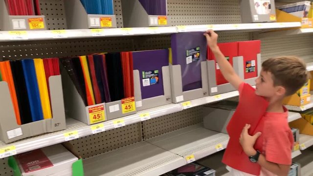 Little boy shopping for back to school supplies in store