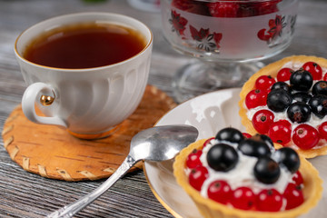 Cup of tea and baskets with cream and currant