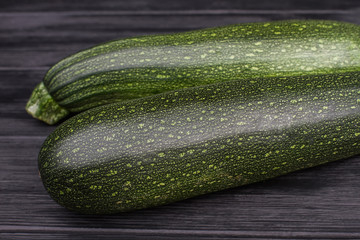 Big green zucchini close up. Black wooden table background.