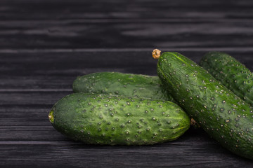 Pile of green fresh cucumbers. Black wooden table backhround.