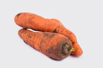 Pile of raw orange dirty carrots. White isolated background, cutout.