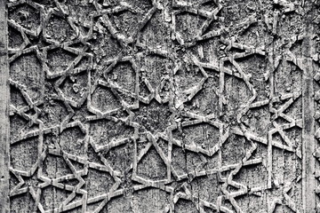 A beautiful carved pattern on an ancient weathered wooden door . Beautiful vintage background in oriental Uzbek style. Black and white view