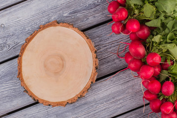 Rustic round cut board and radishes. Top view flat lay. Grey wooden table background.