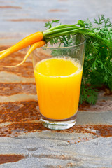 A glass of carrot juice and young carrots.