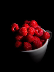 Raspberry in a mug on a black background.