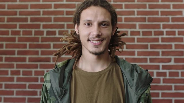portrait of attractive young mixed race man with dreadlocks smiling happy looking relaxed at camera