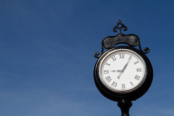 Old Black and White Street Clock with Roman Numerals Outdoors