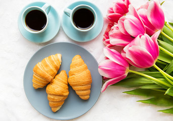 two cups of coffee, croissants and a bouquet of pink tulips, beautiful morning