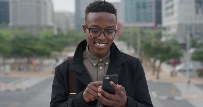 portrait young african american businessman student using smartphone in city texting browsing messages on mobile phone enjoying professional urban lifestyle slow motion