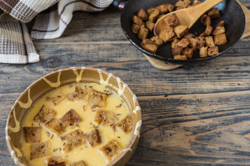 Caraway soup with croutons on rustic wooden table