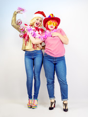Bright fashion portrait of pretty young best friends celebrating Christmas party, having great party time. Sisters spending new year holidays together on a light background