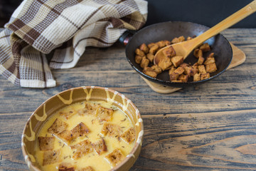 Caraway soup with croutons on rustic wooden table