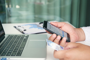 Hand holding mobile phone with Payment Detail page display and credit card, online shopping concepts