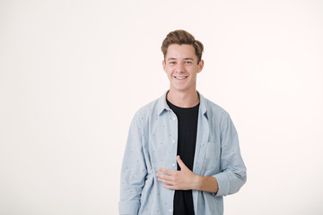 Friendly looking handsome young man wearing blue shirt smiling standing over white background