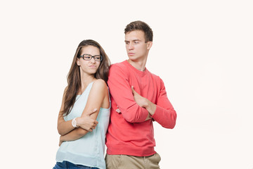 Studio shot of disgruntled couple wearing casual clothes standing back to back frowning their...