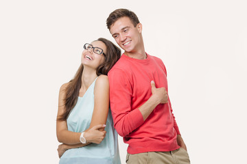 Happy young lovely couple standing back to back and laughing over white background. Friendship and relationships