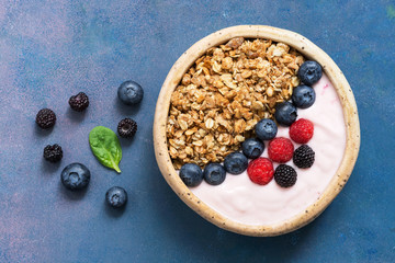 Homemade granola with yogurt, blueberries and raspberries on a blue background. Organic breakfast. The concept of healthy eating. View from above, flat lay,Overhead