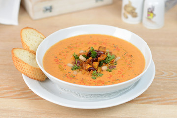 pumpkin soup with beans and croutons on a white plate