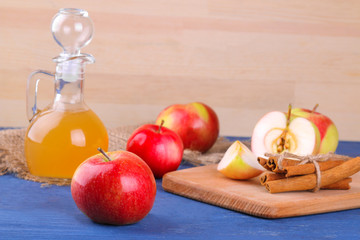 Apple vinegar with fresh ripe apples on a blue wooden background
