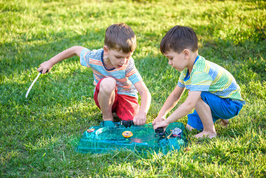 Two Boys Playing With A Beyblade, Spinning Top Kid Toy. Popular Children Game Tournament.