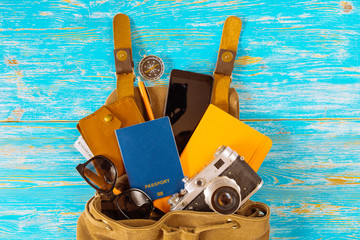backpack with stuff. travel concept. passport money sunglasses on blue wooden background. copy space