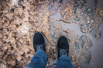 black suede boots on muddy asphalt