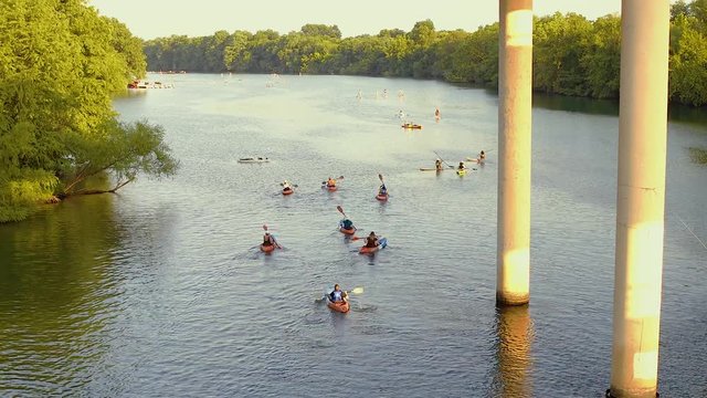 Group of people on kayaks rowing under a bridge in Austin Texas.