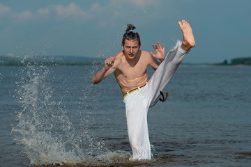 Person practicing capoeira on the beach is a concept of people, lifestyle and sports. Man doing...