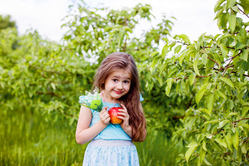 little girl in summer in green with red apple
