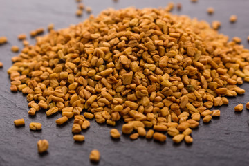 fragrant grains of fenugreek on a rustic background
