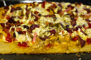 homemade pizza with peppers, plums, ham, sausage, cheese and spices, closeup