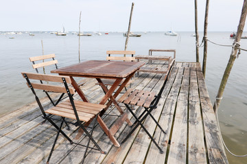 wooden chairs and tables installed on a pontoon at the edge of the arcachon basin in France