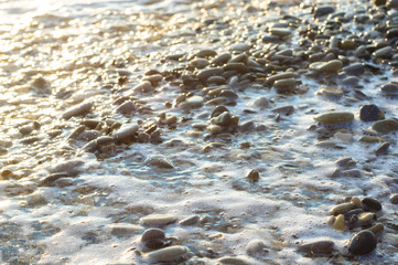 pebble stones on the sea beach, the rolling waves of the sea with foam
