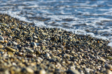 pebble stones on the sea beach, the rolling waves of the sea with foam
