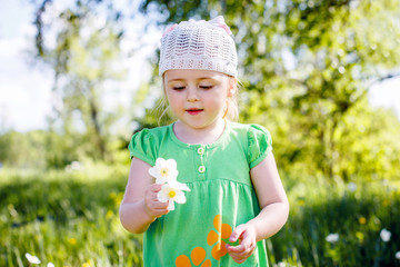 little girl in a green dress in a clearing in the summer with flowers