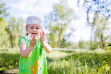 little girl in a green dress in a clearing in the summer with flowers