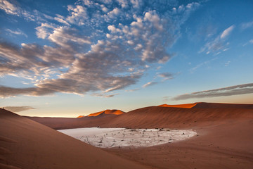 Fototapeta na wymiar Dead Vlei with the dry white mud bottom and dead trees in the Sossusvlei Area seen from Big Daddy with sunrise in Namib Naukluft National Park in Namibia