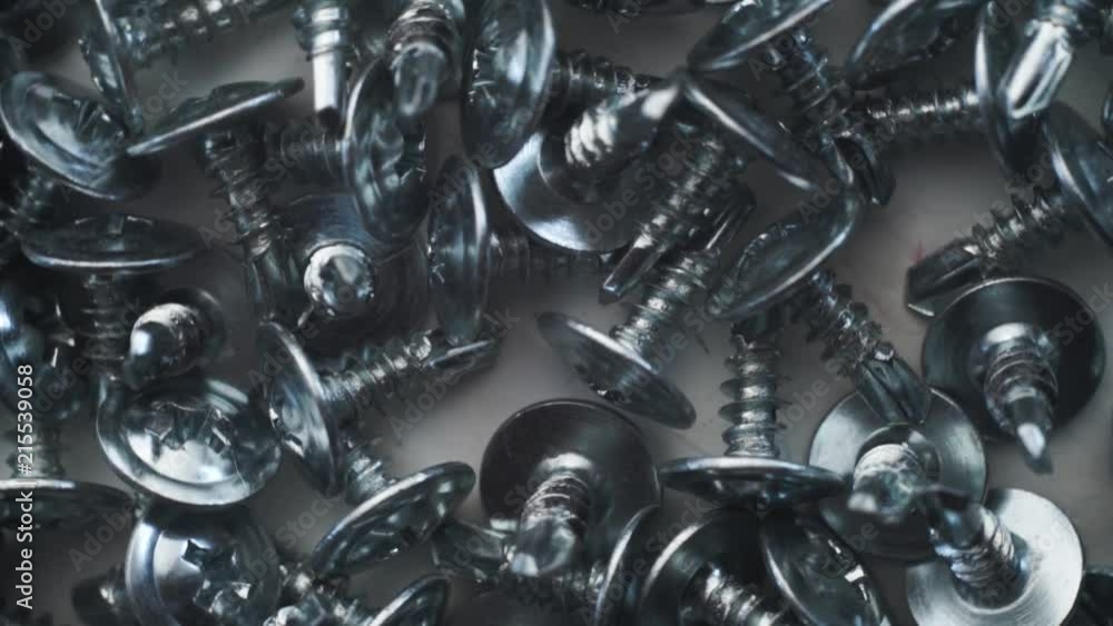 Aufkleber Macro screws rotating on a metal table and black background. Seamless loop.