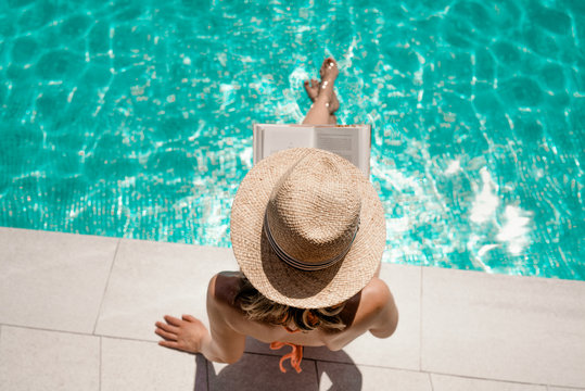 Frau am Pool liest Buch