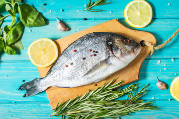 Raw fresh dorado with lemon on blue wood stone background.
