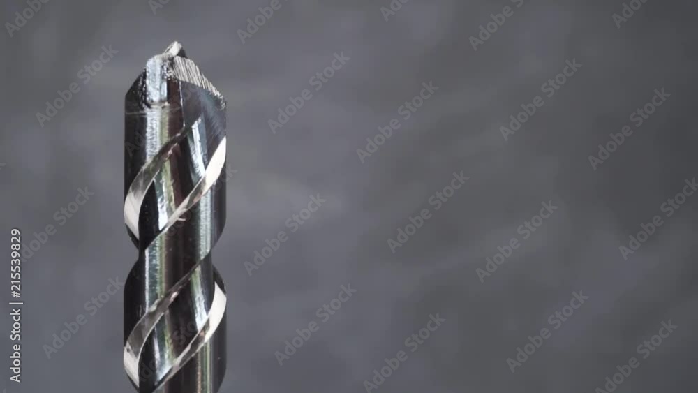 Poster Silver drill bit rotation on a dark background. Macro view.